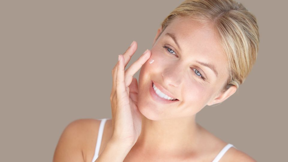 Kvinne påfører fuktighetskrem på ansiktet 