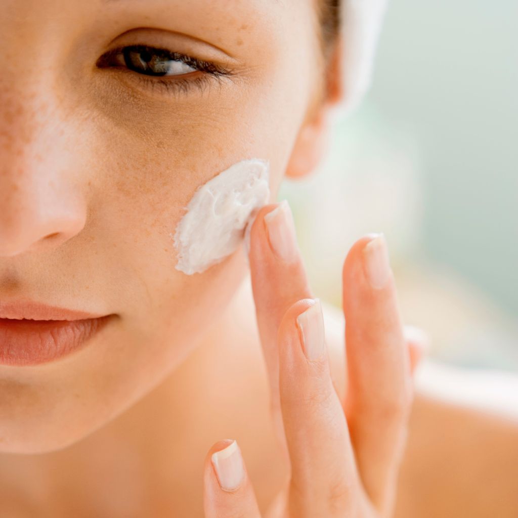 Kvinne smører hudkrem på ansiktet 