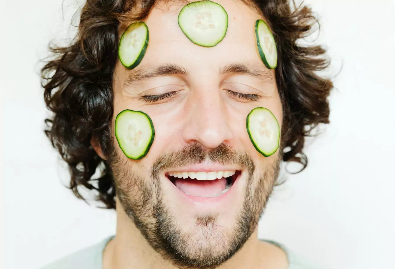 mann med agurkskiver i ansiktet
